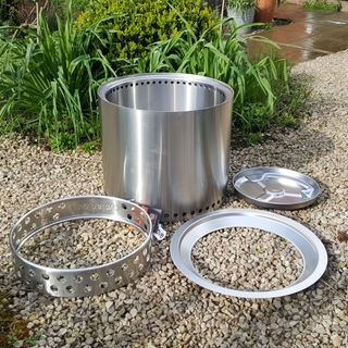 The stainless steel Solo Stove Ranger fire pit being assembled in a gravel garden