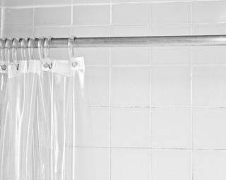 Clear shower curtain with a white tile shower