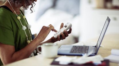 Woman using calculator at laptop