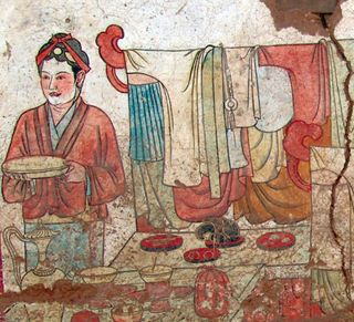 A close-up showing part of the mural on the west wall. The servant appears to be preparing a meal.