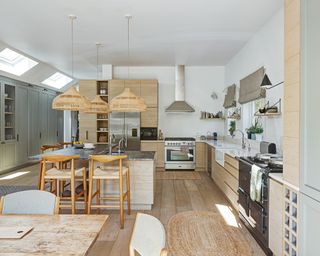A large white L-shaped kitchen with rattan rug and lighting.