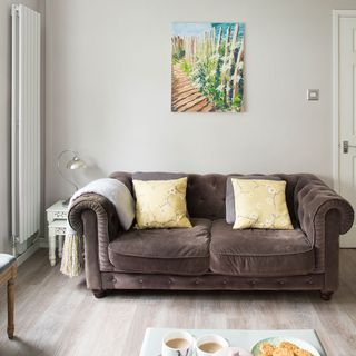 living room with grey wall brown sofa and wooden flooring