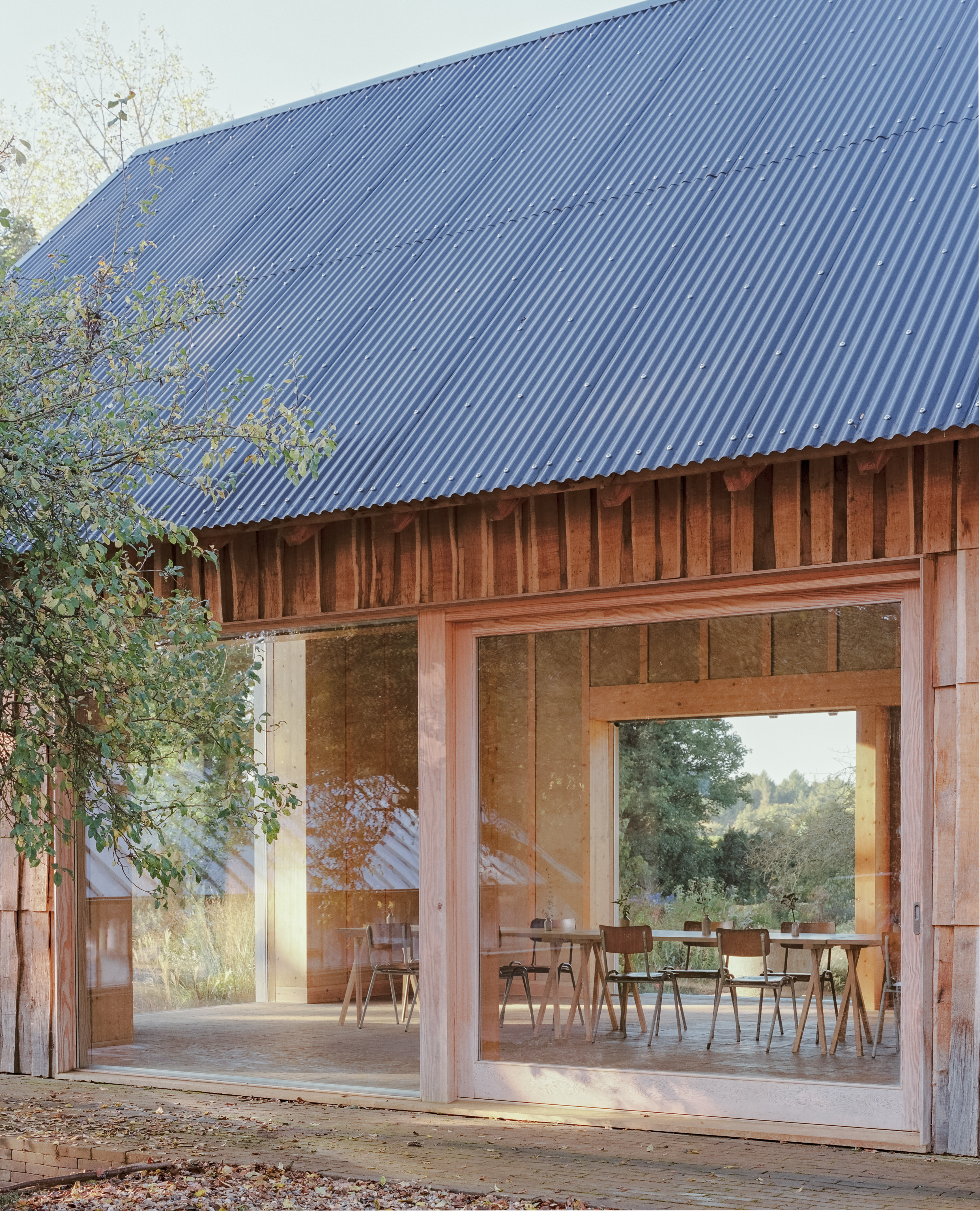 The Apple House, timber building with shingles and pitched roof set among wildflower fields