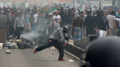 A pro-Palestinian protester throws a projectile at a French police officer