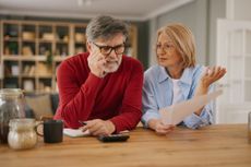 Senior couple analyzing expenses, facing financial stress with monthly bills