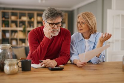 Senior couple analyzing expenses, facing financial stress with monthly bills