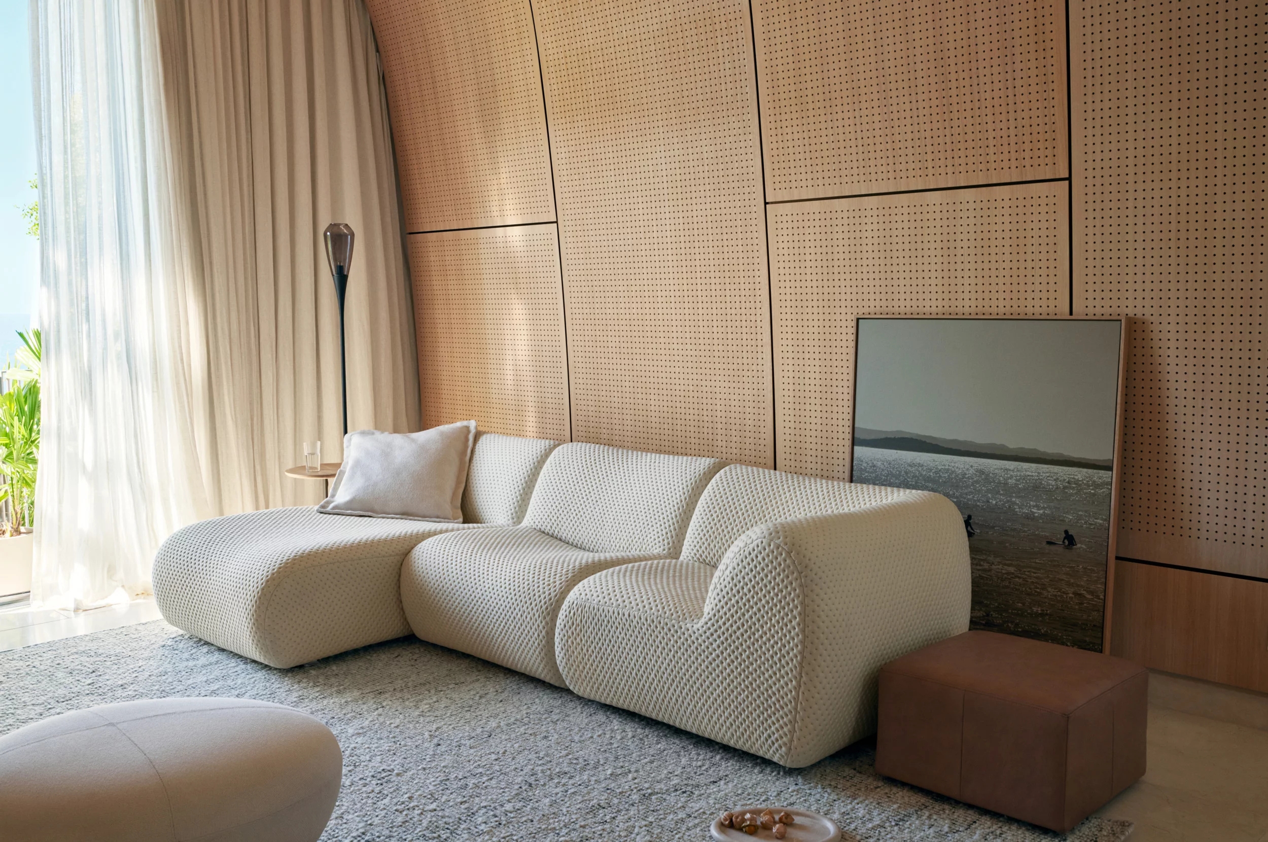 a white curvy sofa in a timber clad room with art behind it