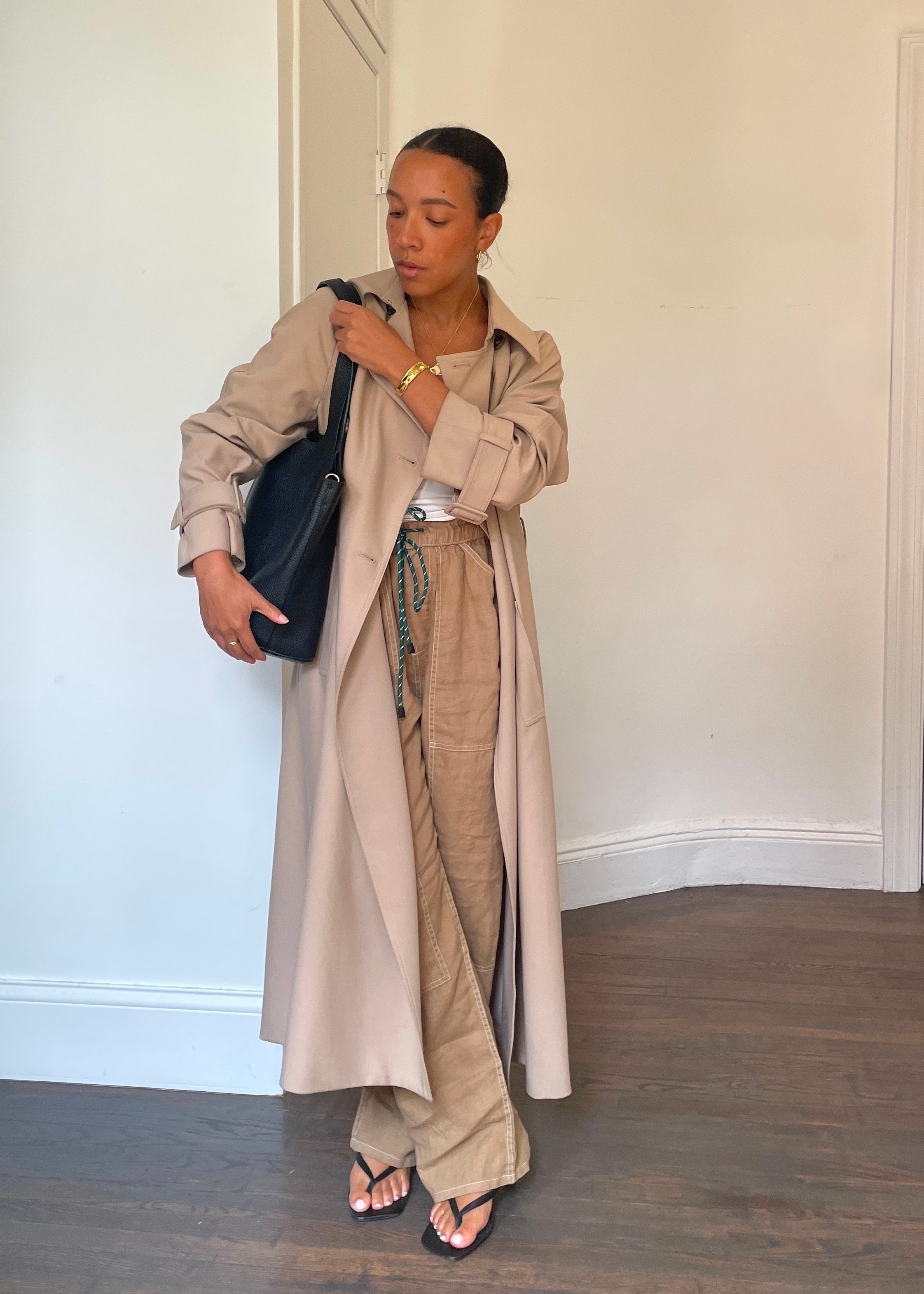 Lauren Tappan wearing rag &amp;amp; bone atlas pants with white tank top, trench coat, black tote, and black thong sandals