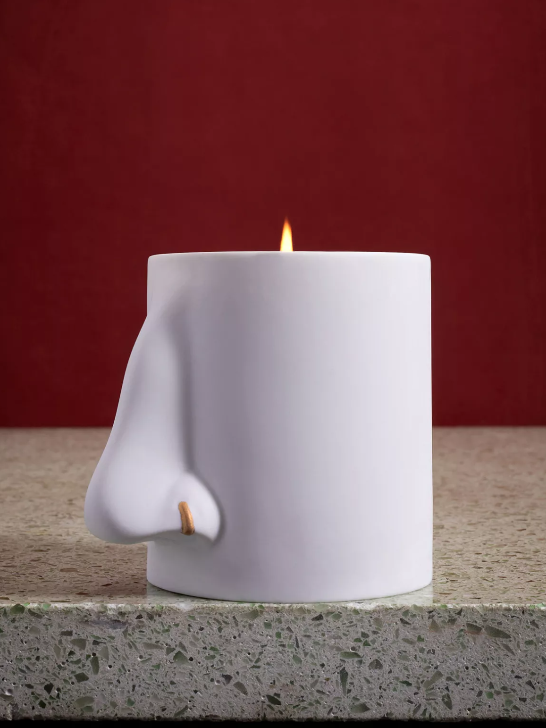 A white scented candle with a ceramic nose design from L'Objet