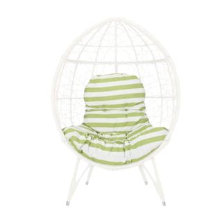 A white woven outdoor egg chair with a white and green striped seat cushion in the middle of it and four legs standing it up