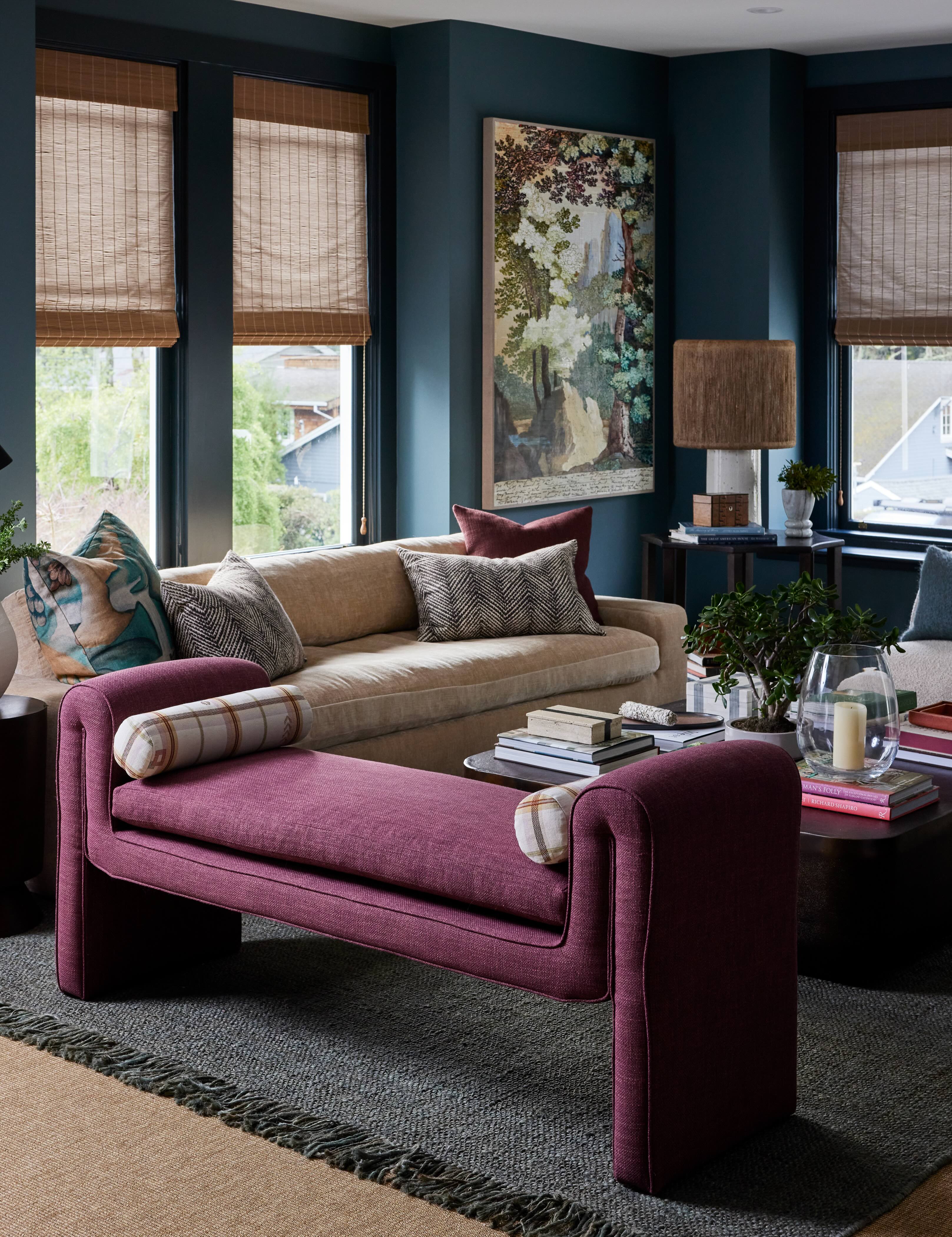 A small living room with sofa, bench and armchair, plus central coffee table and wall art