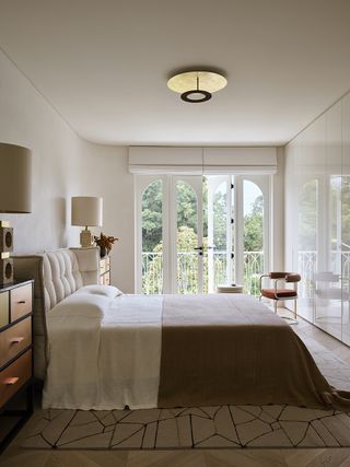 white bedroom with orange chest of drawers and armchair