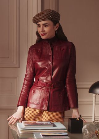 Lily Collins wearing a beret, a leather jacket, and a plaid skirt