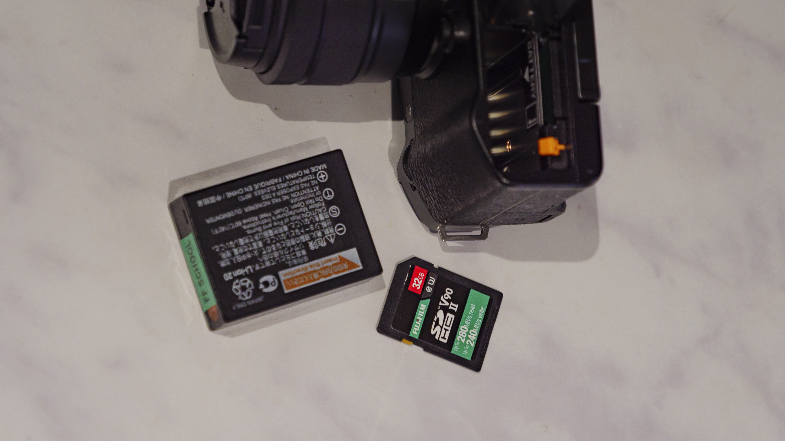 The battery and a memory for the Fujifilm X-M5 camera on a marble surface