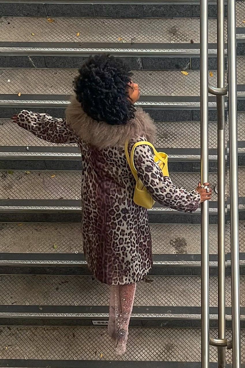 A woman wearing a leopard print jacket with a yellow handbag