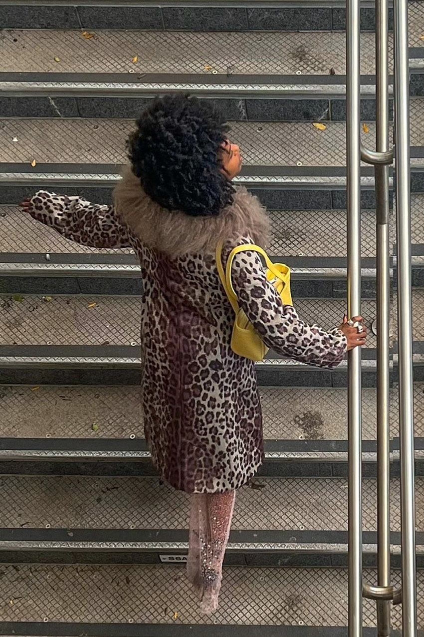 A woman wearing a leopard print jacket with a yellow handbag