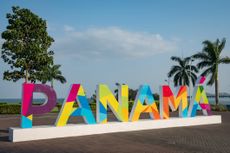 A large and colorful sign that says Panama with palm trees and blue sky in the background