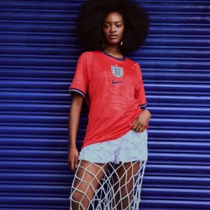 Woman wearing football jersey and fishnet skirt leaning on blue metal door