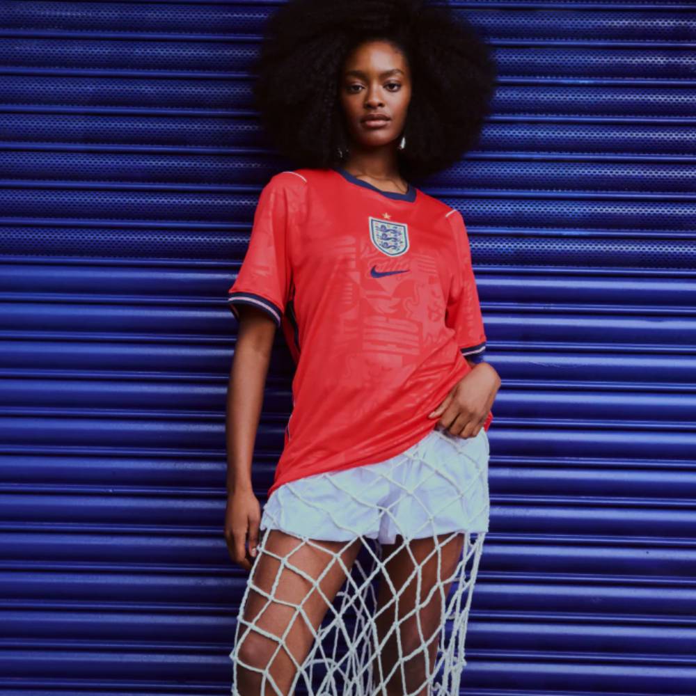 Woman wearing football jersey and fishnet skirt leaning on blue metal door