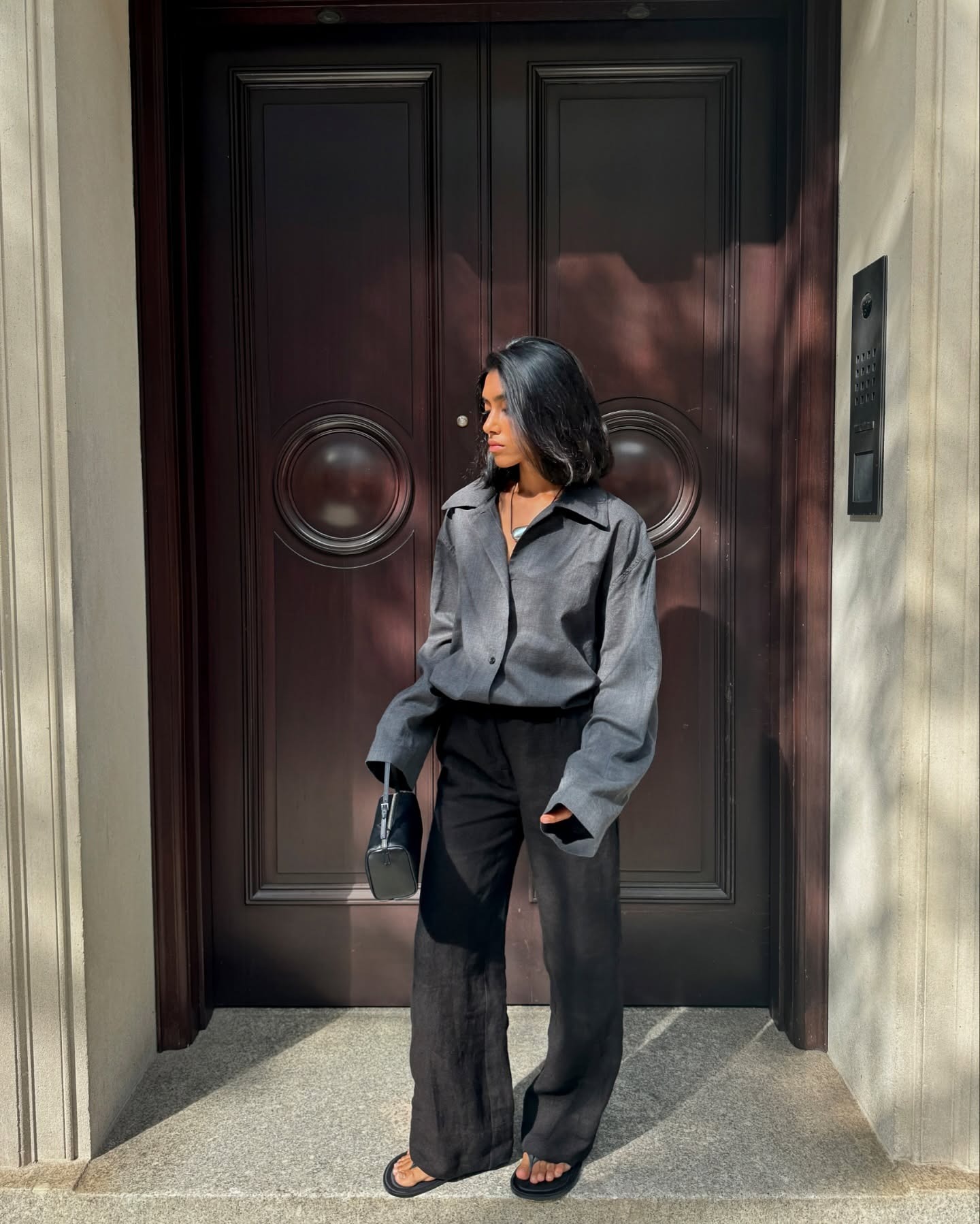 @shayinjune wearing a gray button-down shirt with black trousers and flip-flops.