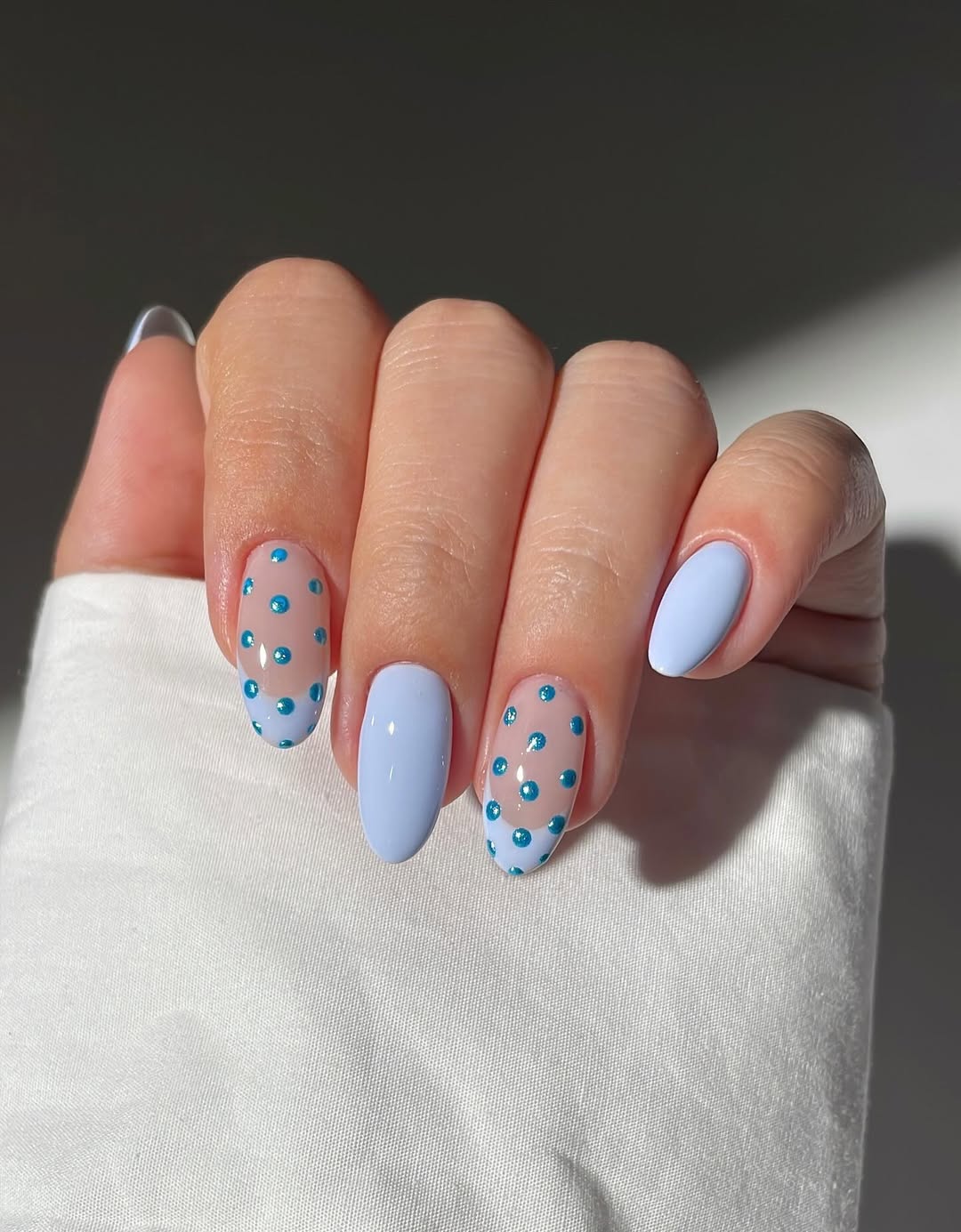 a nail photo featuring light blue nails with blue chrome polka dots