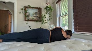 Reviewer Alex laying on her side on the Bear Elite Hybrid mattress