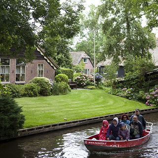 sloping roof house with grass lawn and red boat on waterways