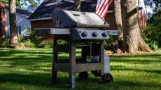 A Weber Spirit II E-310 in a suburban yard with an American flag