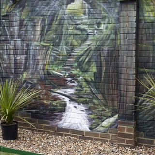 garden with gravel and wall mural on brick wall