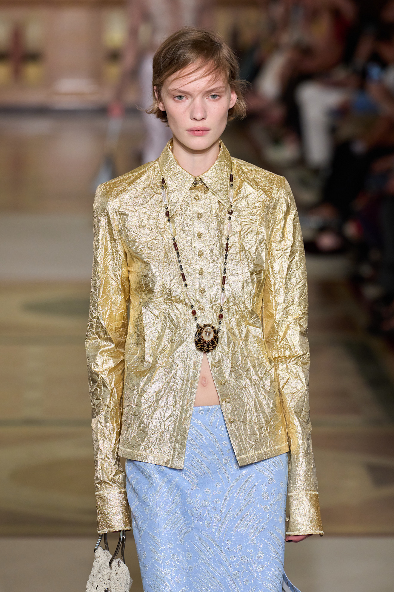 A model at the spring/summer 2026 show for Tory Burch wearing a metallic gold shirt.