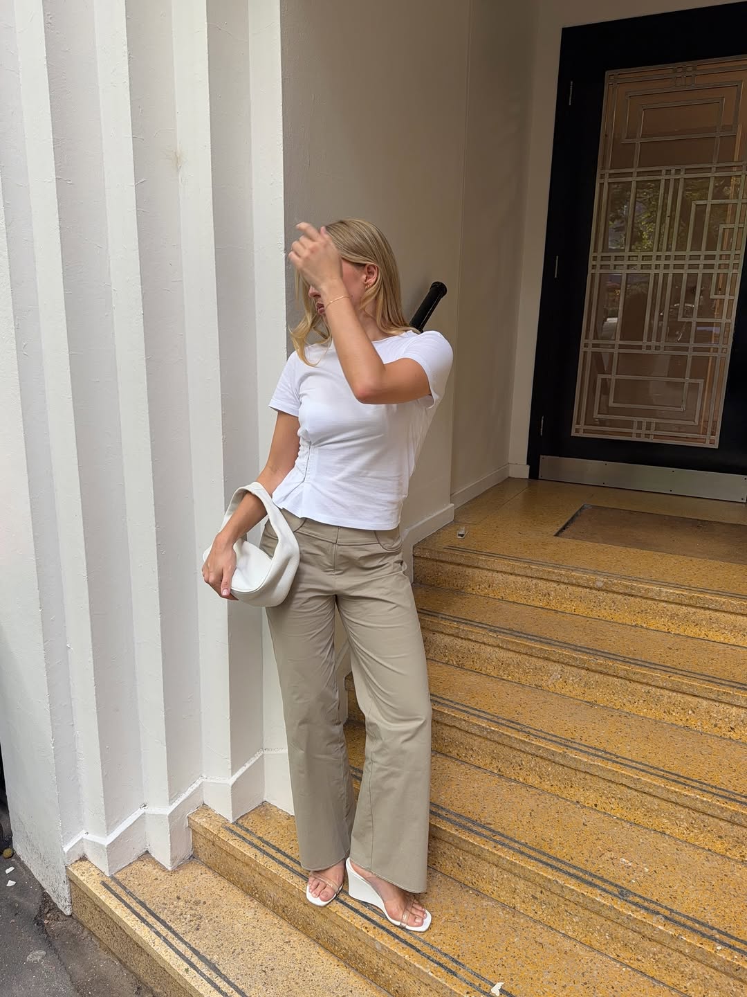A woman wearing a white T-shirt and neutral trousers, part of the Spring Basics Outfit 2026.