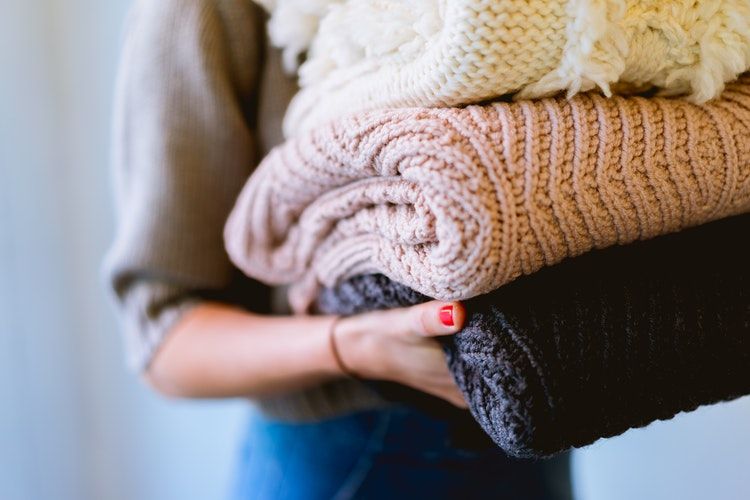 how to wash clothes by hand - a women tidying away folded clothes to organise her home