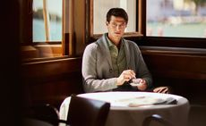 Male wearing knitted cardigan drinking coffee
