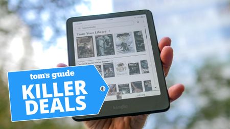 Kindle Colorsoft held in hand with trees in background