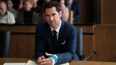 Mickey Haller sits at a desk in a court room with a bandaged hand in The Lincoln Lawyer season 2