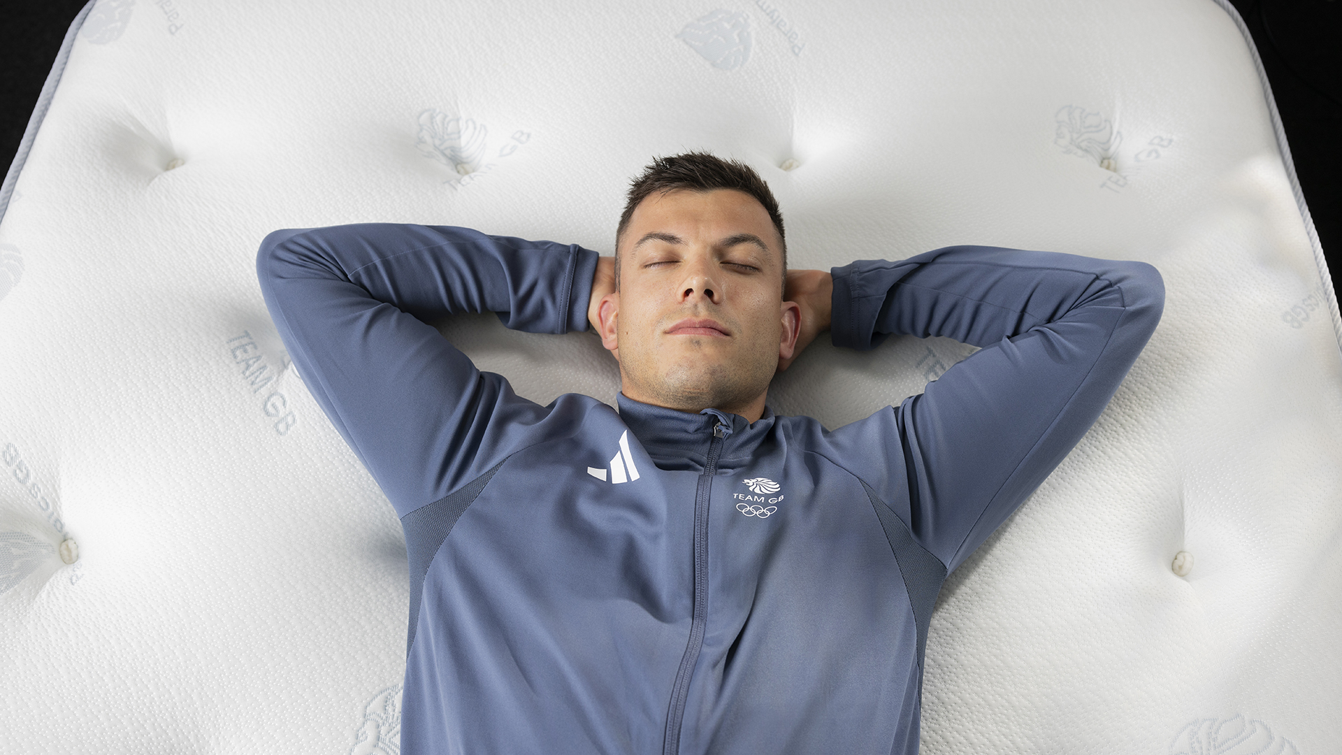 Team GB Olympic Skeleton competitor Matt Weston lying on his back on a Dreams Dream Team mattress