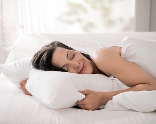 woman hugging a white pillow in bed - tempur