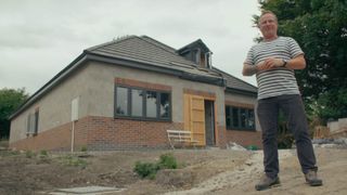 Mark Millar stood in front of shell of newly built bungalow