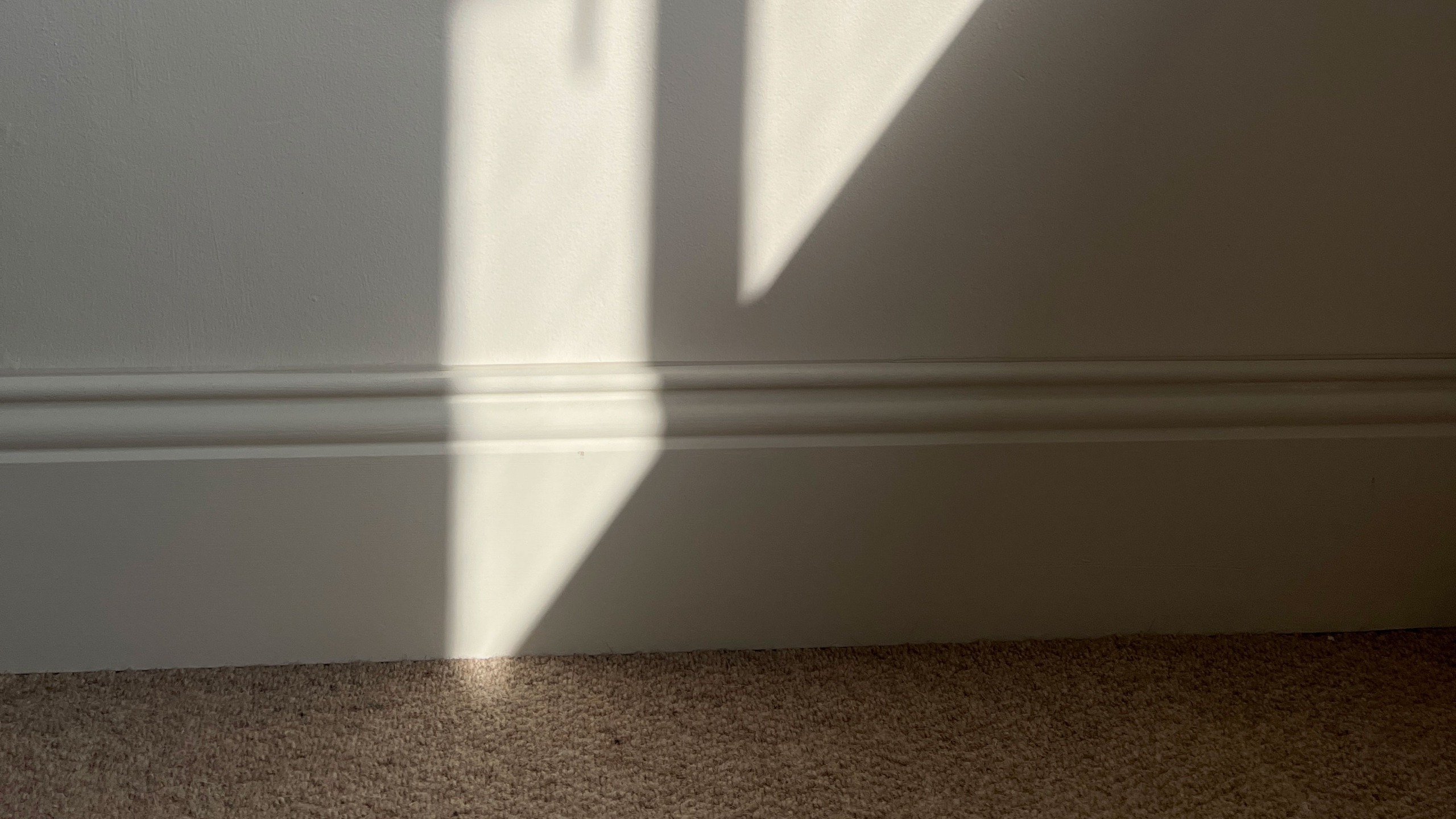 Sunlight cast onto white wall and skirting board