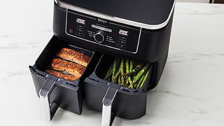 The Ninja Foodi Dual Zone air fryer with chicken in one frying drawer and asparagus in the second frying drawer