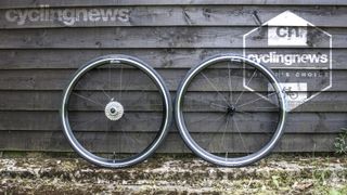 Scribe Pace rim brake wheels resting against a wooden backdrop