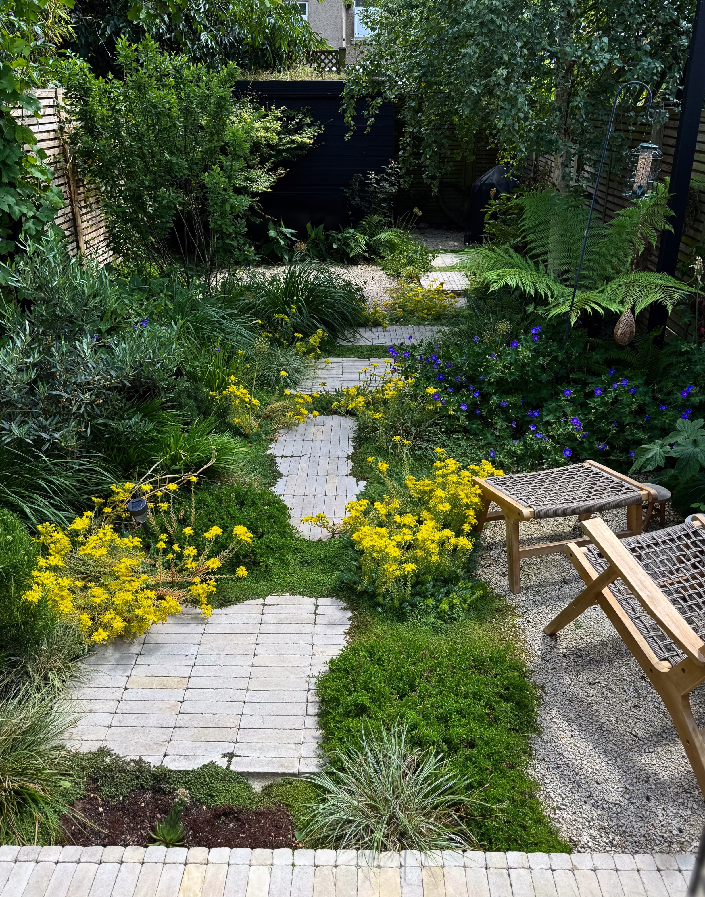 a garden with a stacked bond rectangular paver path
