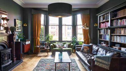 Living room with dark teal walls, leather sofa and fireplace