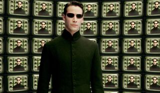 Keanu Reeves stands in front of The Architect's monitors in The Matrix Reloaded.
