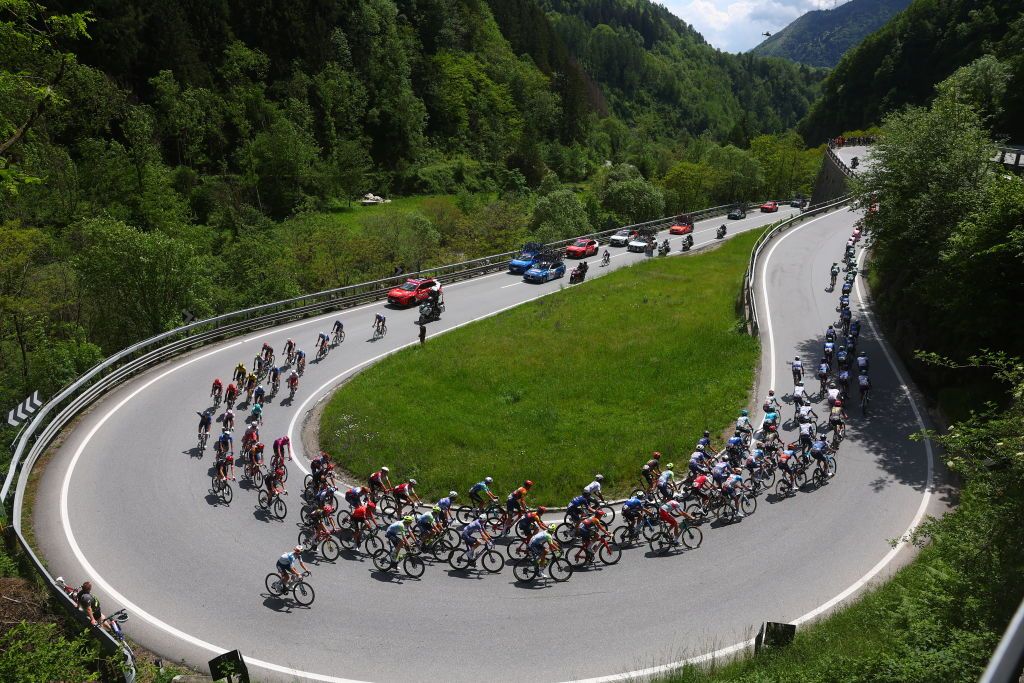 The pack rides in a curve of Edolo during the 15th stage of the 107th Giro d'Italia cycling race, 222km between Manerba del Garda and Mottolino on May 19, 2024. (Photo by Luca Bettini / AFP)