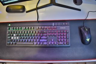 A full-size black keyboard with a mouse on a desk.