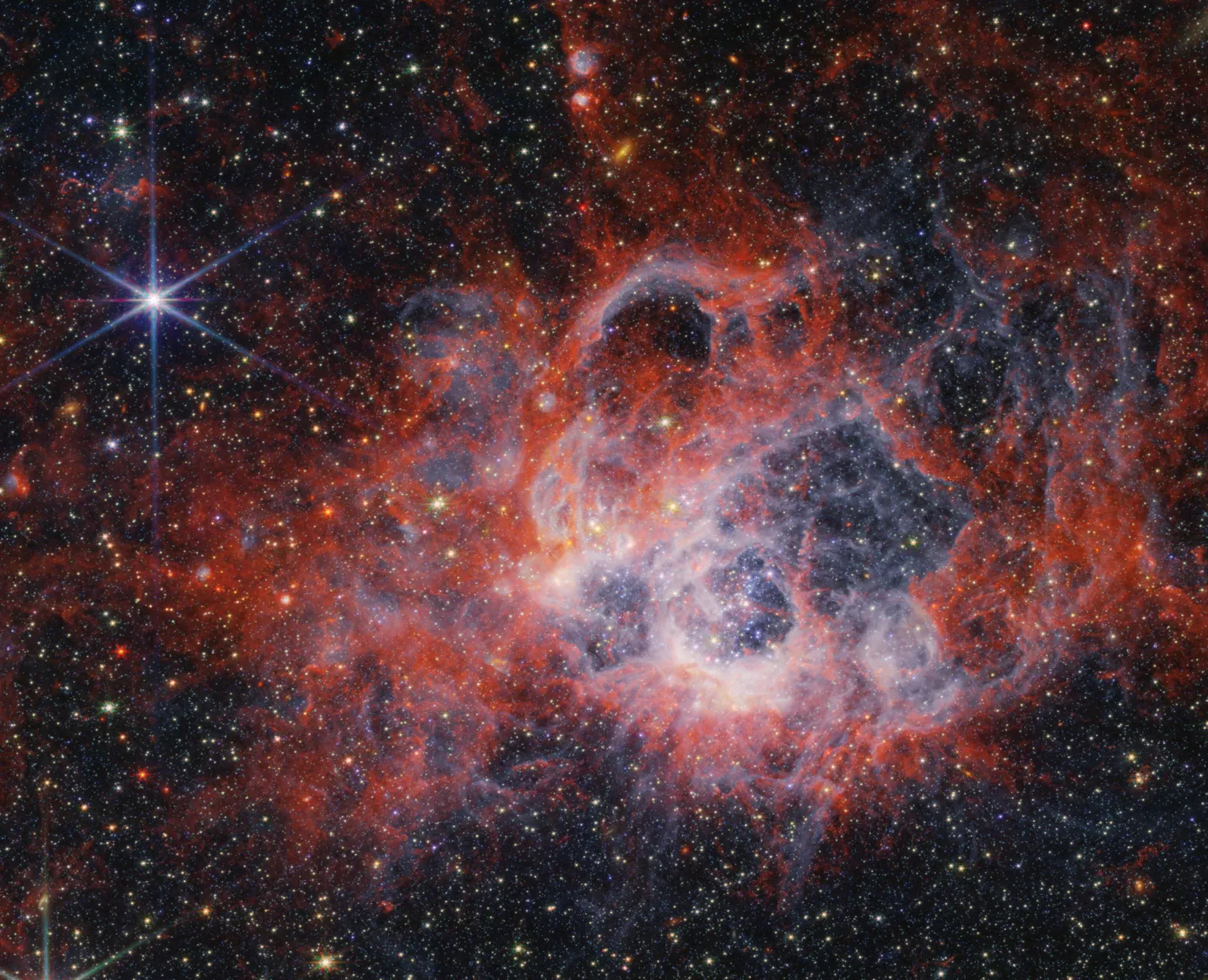 This full image from NASA’s James Webb Space Telescope’s NIRCam (Near-Infrared Camera) of star-forming region NGC 604 shows how stellar winds from bright, hot, young stars carve out cavities in surrounding gas and dust.
