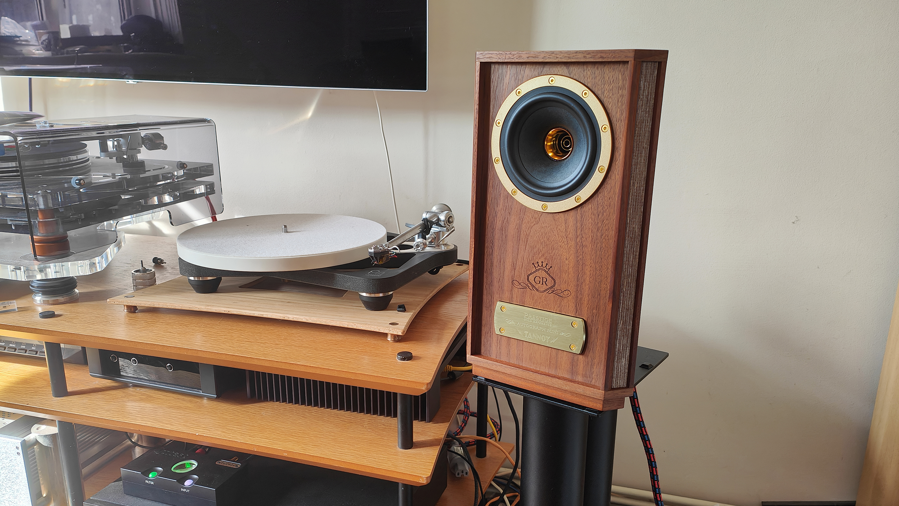 The Tannoy Autograph Mini pictured in a room next to a wooden sideboard and a record player