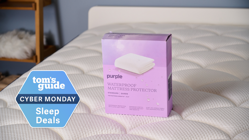 The Purple Waterproof Mattress Protector in the package placed on the bed in our TG Sleep Studio with TG Cyber Monday Sleep Deals badge on the left side