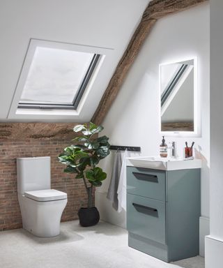 loft conversion bathroom with exposed brick lower section on wall, white velux light, small blue vanity unit and some exposed beams